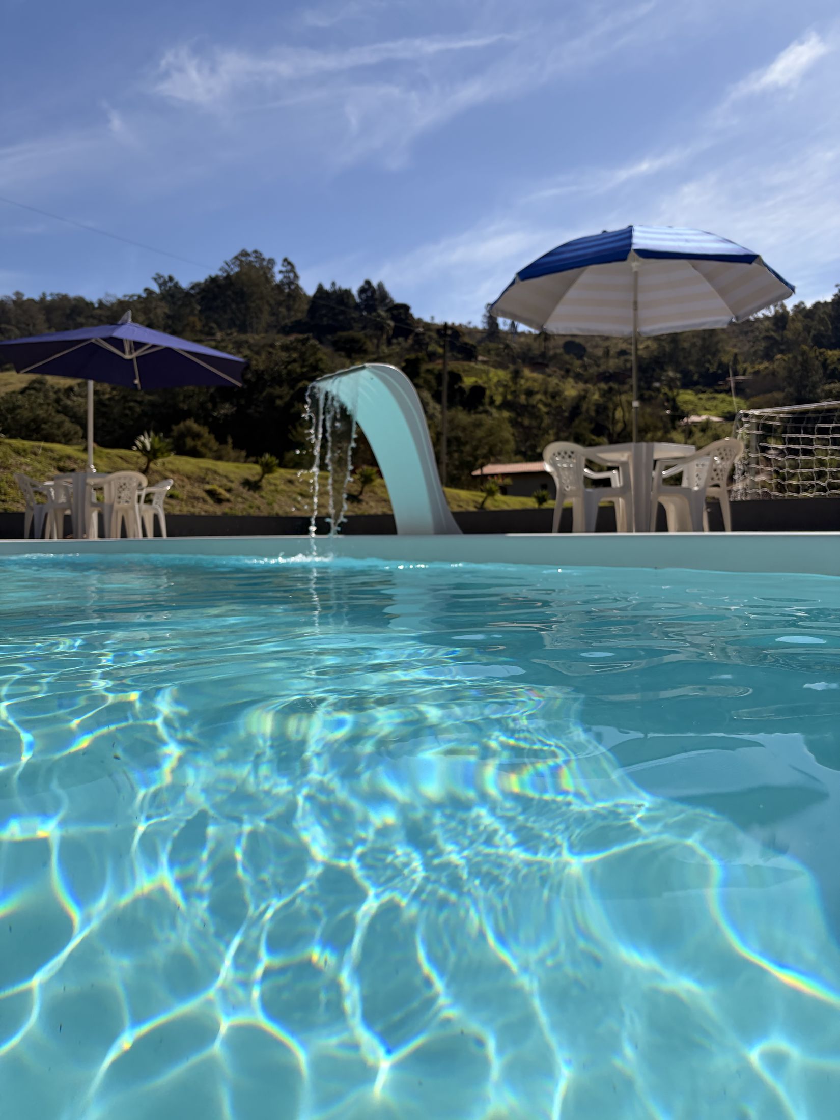 Piscina ao ar livre com cascata e guarda-sóis